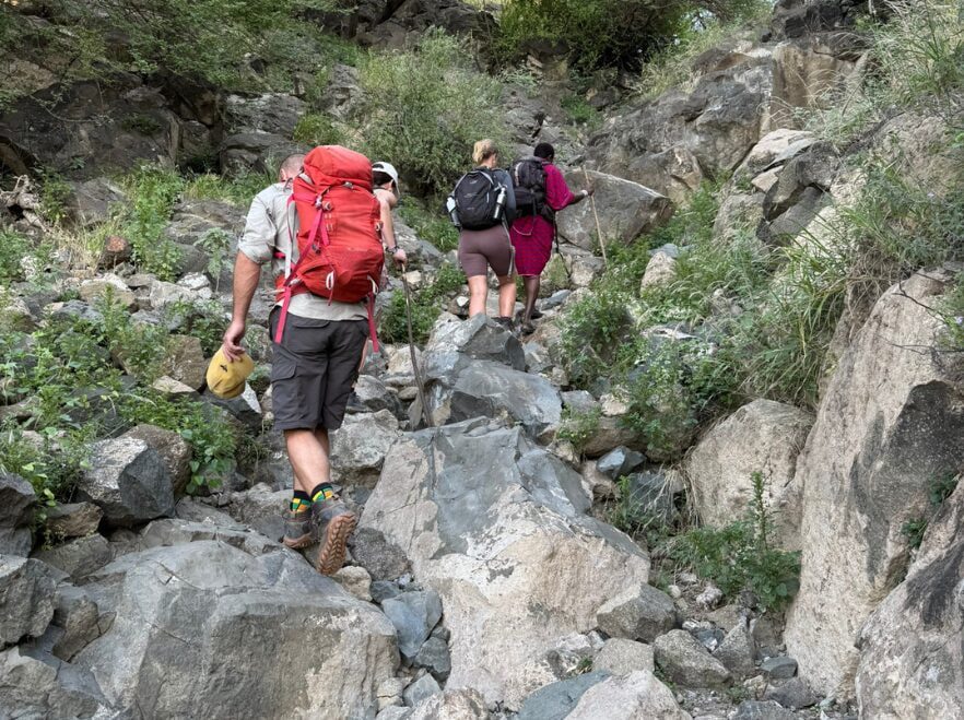 Trekkers helping each other along a rocky trail